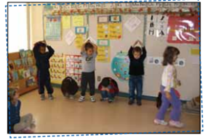 Des enfants réalisent une suite à motifs répétés avec leur corps. Ils alternent entre la position debout et main sur la tête et accroupi au sol, répété 2 fois. »