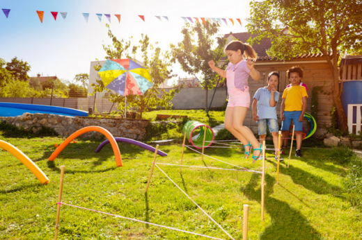 Des enfants qui jouent dans un jardin avec des jeux d’obstacles.