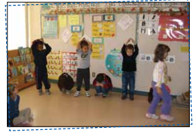 5 enfants réalisant une séquence avec les corps. Ils alternent entre la position debout et mains sur la tête et accroupi au sol.