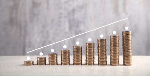 Stacks of coins are lined up from the smallest to the largest stack. A hand places a coin on the largest stack. A line follows the slope of the coin piles.