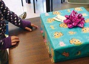 A child measures the length of a gift using paperclips as a unit of measurement.